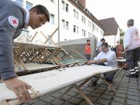 „Besser als der nackte Holzboden“: Auf dem Gelände der Zirndorfer Asylbewerberunterkunft bauen ehrenamtliche BRK- Mitarbeiter Zelte und Feldbetten für Flüchtlinge auf. Foto: Hans-Joachim Winckler