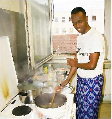 Abdi Khani bereitet sich sein Essen zu. Die Bewohnermüssen sich nicht nur die Bäder teilen, sondern auch die Küchen. Foto: Simone Bastian